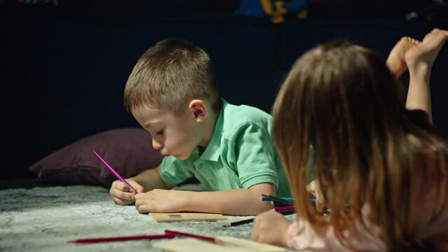 Capturing the Essence of Childhood: Siblings Cherishing Quality Time as They Express Their Imaginations through the Joy of Drawing on the Living Room Floor. High quality 4k footage