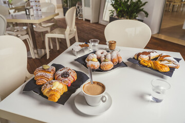 breakfast with cup of coffee and croissants on a white table. Front view