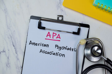 Concept of APA - American Psychiatric Association write on paperwork with stethoscope isolated on Wooden Table. - obrazy, fototapety, plakaty