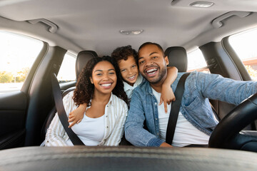 Cheerful loving black family posing in car, going vacation