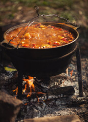 Tourist pot over camp fire. Cooking in field conditions, boiling pot at the campfire on picnic. A...