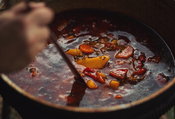 Tourist pot over camp fire. Cooking in field conditions, boiling pot at the campfire on picnic. A cauldron for cooking is on the fire in the open air. Soup on a fire. Food outdoors. Kettle goulash.