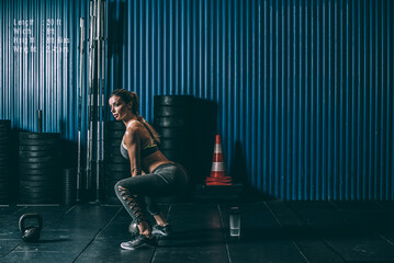 Fit woman profile training working out lifting  kettlebell in Gym