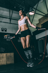 Fit blonde woman jumping rope training working out in Gym