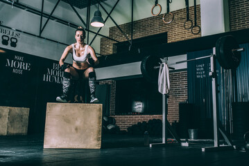 Fit blonde woman jumping box training working out in Gym