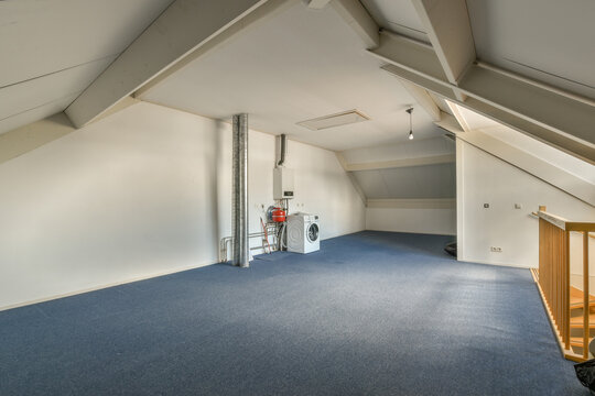 Attic room with blue carpeted floor and white wall