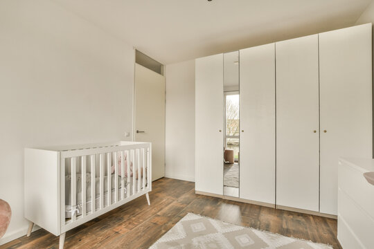 White crib and wardrobe in baby room at home