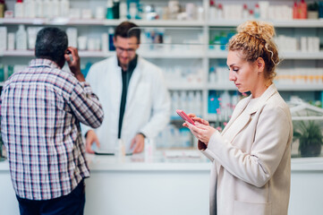 Portrait of a woman customer in a pharmacy using a smartphone