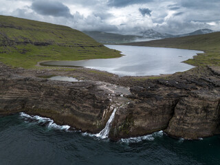 Fototapeta na wymiar Waterfall and Cliffs of Traelanipa with the lake above the ocean, Faroe Islands, Denmark, Europe, aerial view