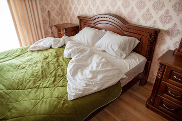 Bedroom interior. Wooden bed with pillows and blanket with white linen and green bedspread