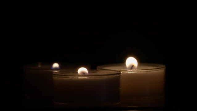 Close-up slow-motion footage of a tea light candles burning in the dark