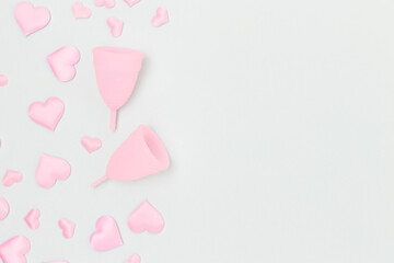 Pink menstrual cups and confetti in a heart shape on a blue background. Concept with place for text.