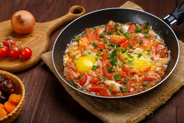 fresh hot shakshuka in a frying pan sprinkled with green onions on a set Shabbat table.