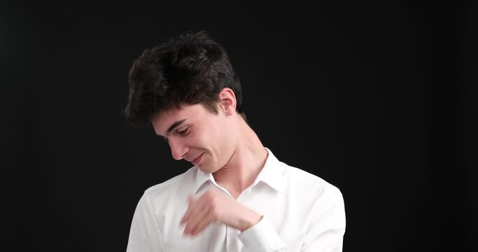 Charming Caucasian man experiences a touch of uncertainty and shyness on a black background. With eyes filled with tenderness and hesitation, he displays a hint of embarrassment.
