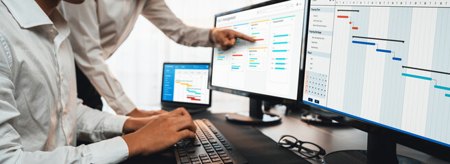 Project management team coordinating and update project planned schedule on computer using Gantt...