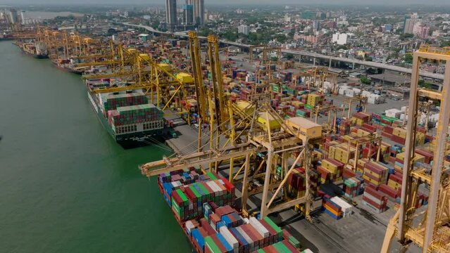 Huge cranes loading large cargo ships. Fly over container terminal in seaport. Rows on stacked containers in logistic complex. Colombo, Sri Lanka