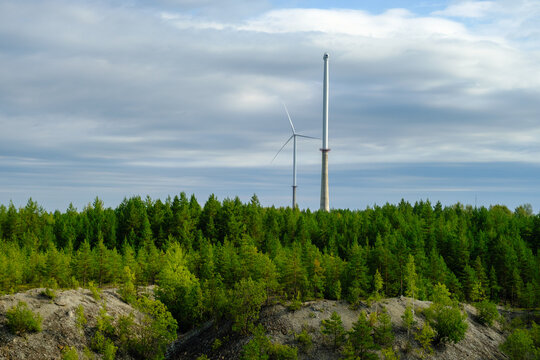 This is a former shale quarry with azure water and picturesque hills. Unlike the Narva shale settling ponds. A dark autumn day. Estonia, Aidu quarry. A tall wind turbine in the distance
