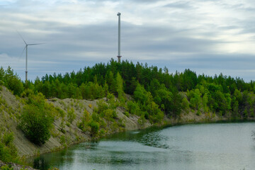 Obraz premium This is a former shale quarry with azure water and picturesque hills. Unlike the Narva shale settling ponds. A dark autumn day. Estonia, Aidu quarry. A tall wind turbine in the distance
