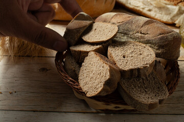 man picking up slices of dark bread on a basket. also known as australian bread.