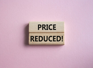 Price reduced symbol. Concept word Price reduced on wooden blocks. Beautiful pink background. Business and Price reduced concept. Copy space