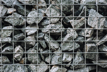 Decorative stones, cobblestones in a metal lattice, cage. Close-up photography, decor.