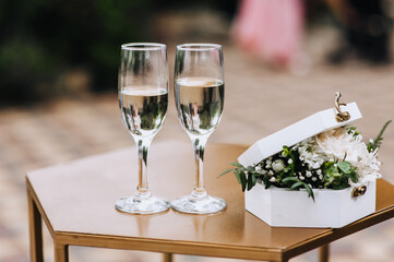 A beautiful box with flowers and glass wine glasses with champagne are on the table at the wedding ceremony. Close-up photography, portrait.