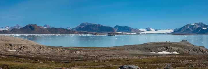 Landing on the shores of the spectacular Kongsfjorden, Spitsbergen, Svalbard, Norway. In the background on the left, the iconic three crown mountain (Tree Kroner) peaks