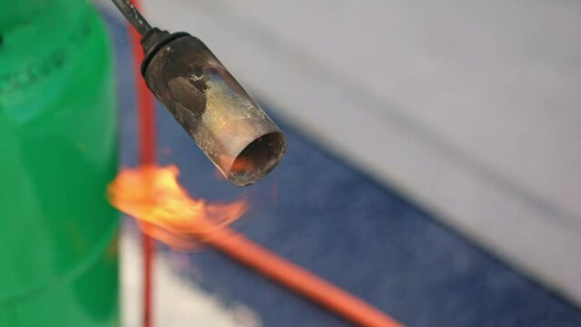 Process of melting roll of tar onto the foundation of a house under construction, waterproofing a developing building, melting a bitumen roll, industrial concept