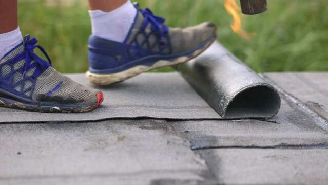 Process of melting roll of tar onto the foundation of a house under construction, waterproofing a developing building, melting a bitumen roll, industrial concept