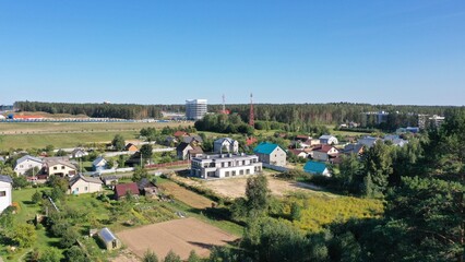 Panoramic views of the modern village. Neighbourhood of private houses (cottages), industrial area and multi-storey residential development. The border of the city and the countryside.