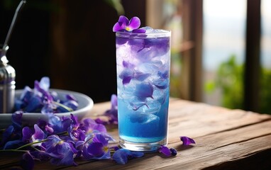 Obraz na płótnie Canvas Blue matcha cocktail in a glass with ice on a table decorated with butterfly pea flowers 
