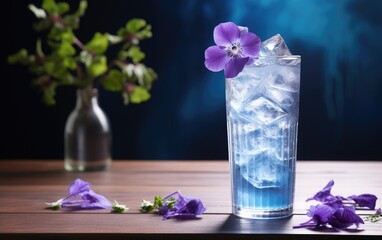 Blue matcha cocktail in a glass with ice on a table decorated with butterfly pea flowers
