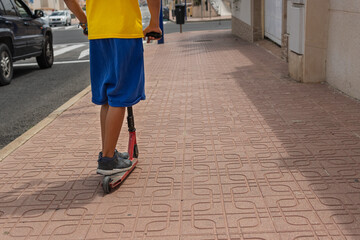 a child in casual clothes rides a scooter on the street, with his back turned to the camera, there is a place for an inscription