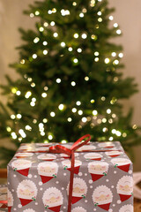 Stylish wrapped christmas gifts against christmas tree with festive lights. Atmospheric Christmas...