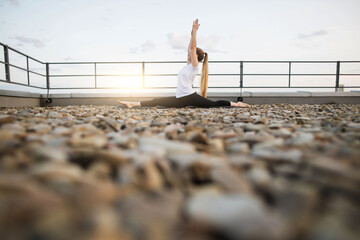 Female performing front split on mat in outdoor yoga session