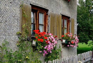 Fototapeta na wymiar traditional Bavarian alpine country house covered with wood shingles with geraniums on window ledge in the Bavarian Alps on September day in Oberjoch, Unterjoch, Bavaria, Germany