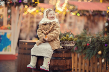 Little russian girl wearing shawl and fur coat on christmas market with lights on background 