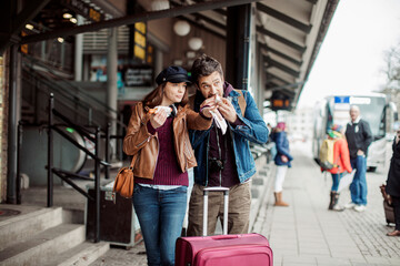 Young couple having a snack while waiting for the bus at the bus station