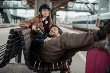 Young couple traveling and waiting for the train at a train station with their suitcases