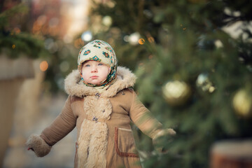 Little russian girl wearing shawl and fur coat with bagels on christmas market 