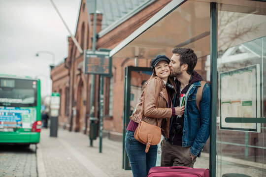 Young couple traveling and looking for directions on a map while waiting for the bus at the bus stop