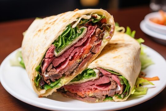 Sliced roast beef wrap with lettuce on a white plate.