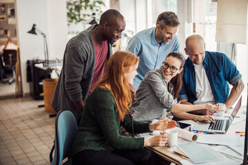 Multigenerational diverse group of architects working together on a project in a startup company office