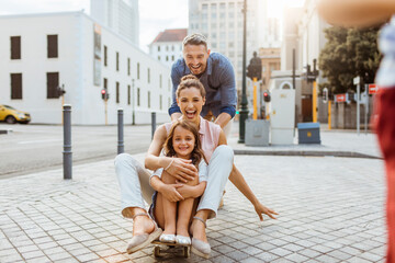 Young family having fun with a skateboard in the city