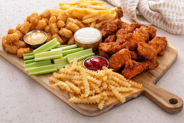 Fried chicken strips and french fries board with sauces and celery