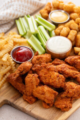 Fried chicken strips and french fries board with sauces and celery