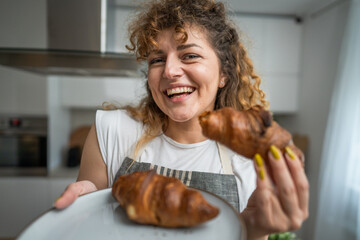 One adult caucasian woman stand in the kitchen with fresh croissant