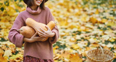 Close up hands of woman embracing rape pumpkins surrounded orange leaves, enjoying autumnal time and seasonal harvest