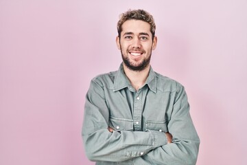 Obraz premium Hispanic man with beard standing over pink background happy face smiling with crossed arms looking at the camera. positive person.