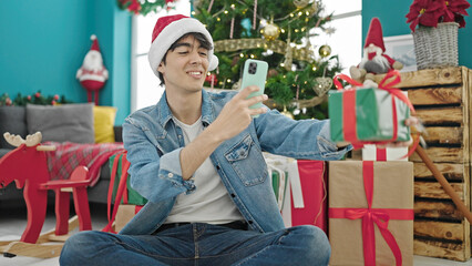Obraz na płótnie Canvas Young hispanic man celebrating christmas make photo to gift at home